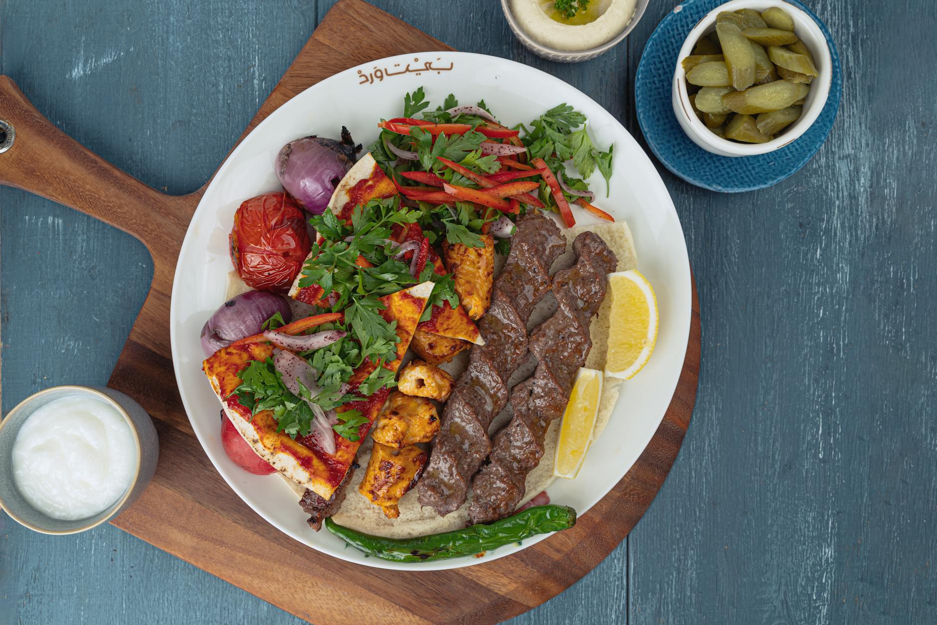 Kolorowy grill z kebabem, warzywami i dodatkami na drewnianej desce