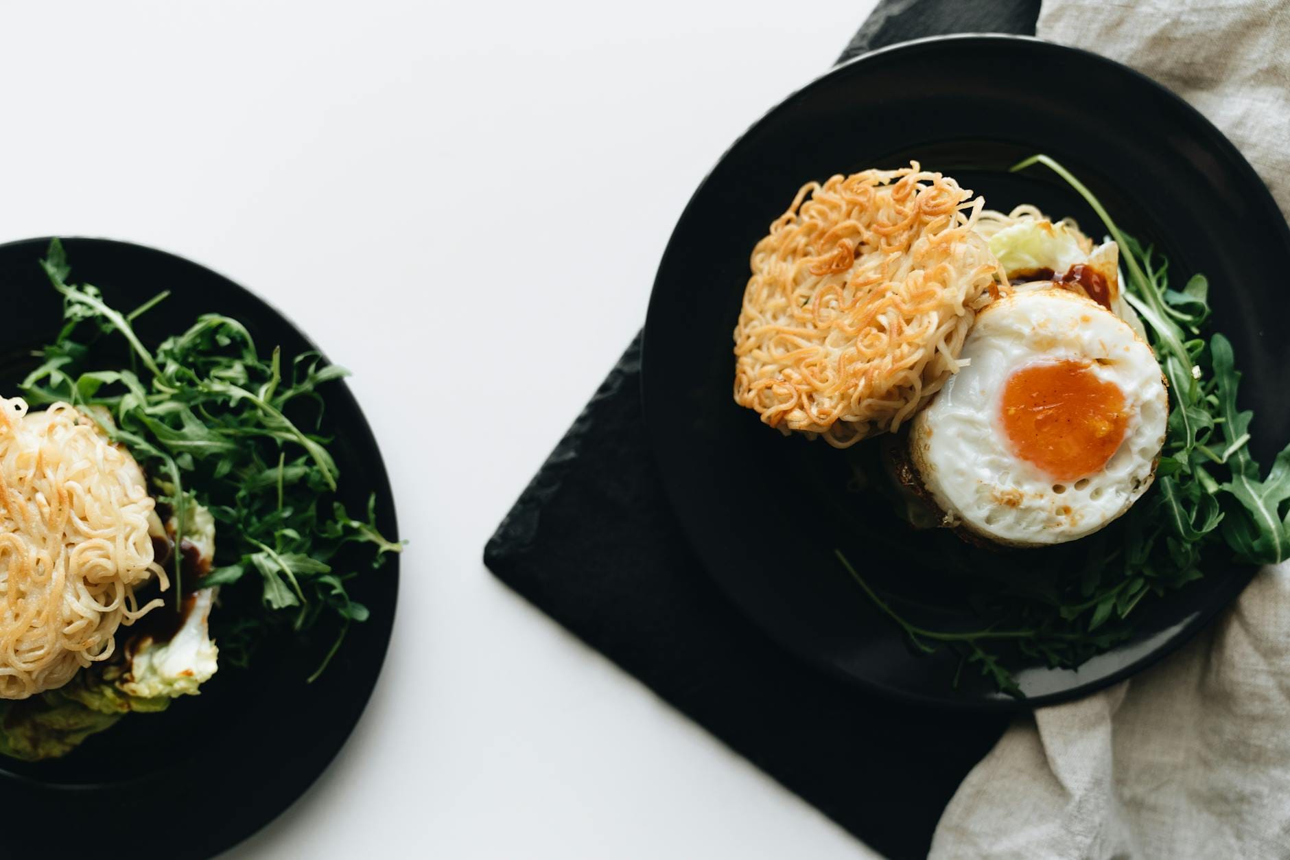 Burger śniadaniowy z bułką z makaronu, jajkiem sadzonym i rukolą