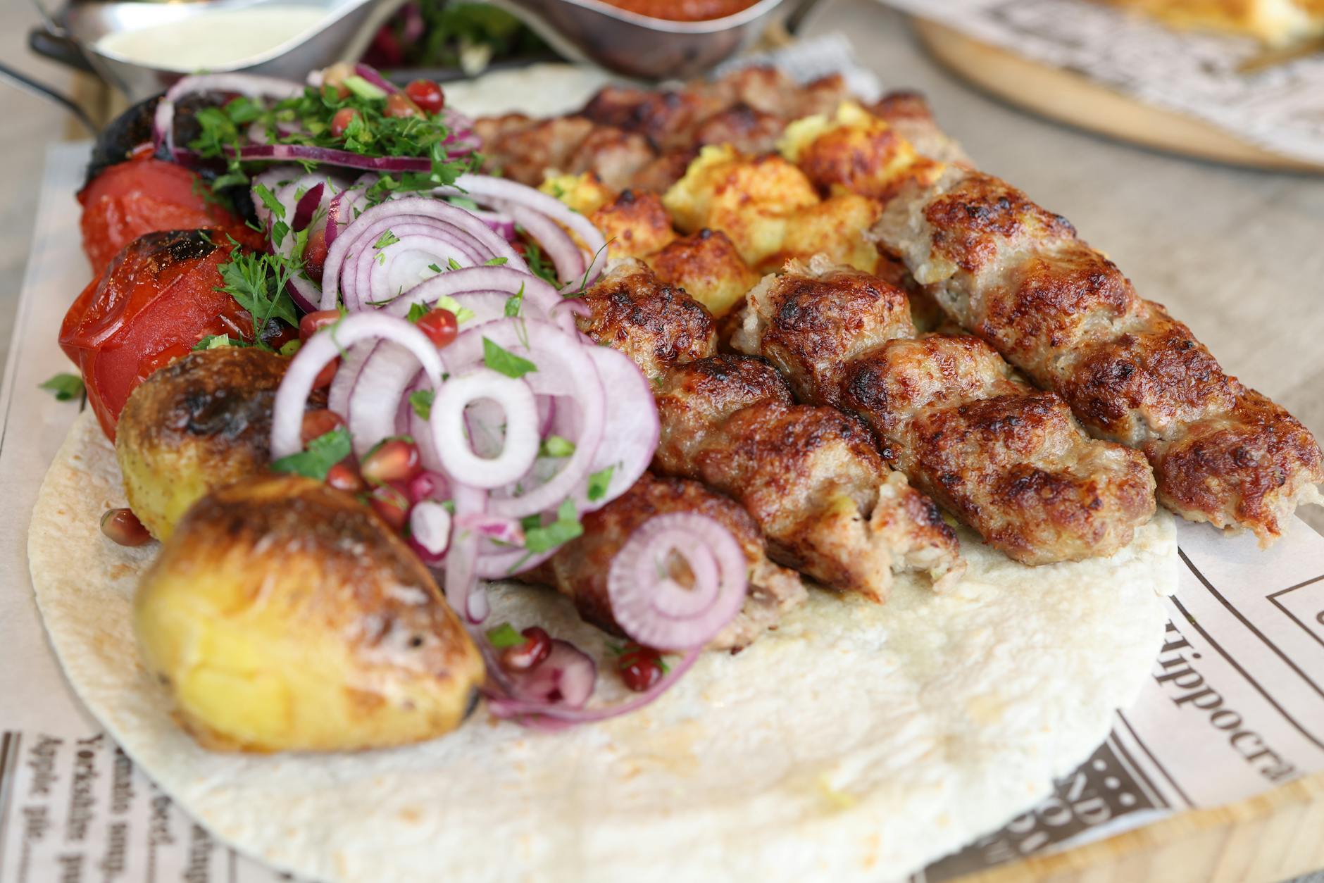 Grillowane mięso z warzywami na placku, posypane ziołami i cebulą