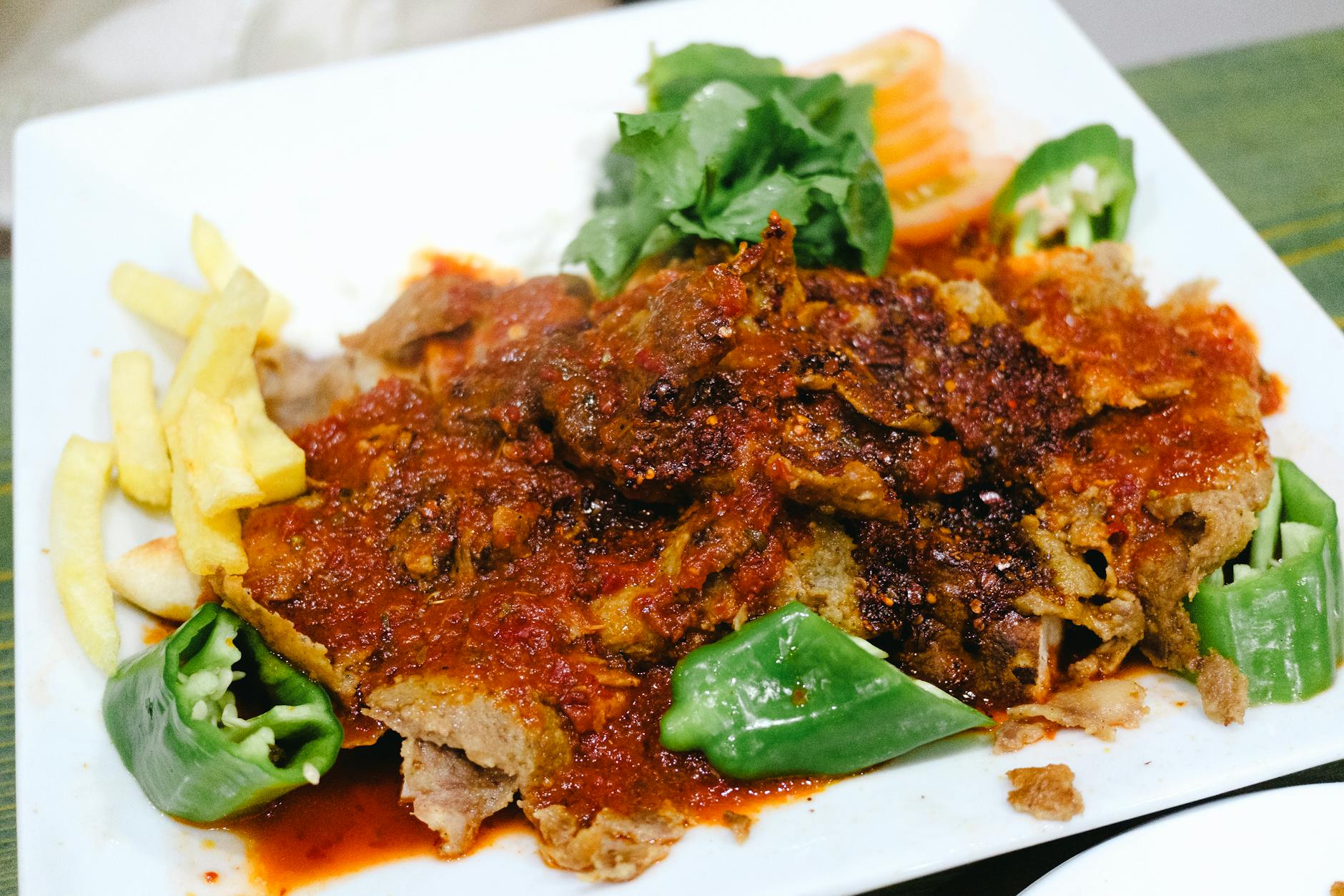 Iskender kebab z frytkami, papryką i sosem pomidorowym na talerzu